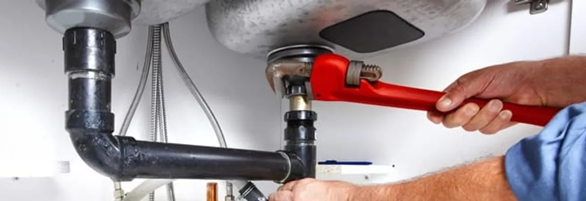 Garbage disposal repair technician tightening the sink drain and disposal connection in Boise, ID