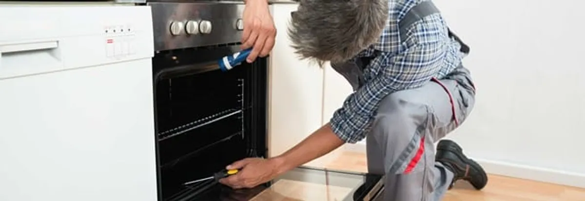 Oven repair technician inspecting and servicing an electric oven in Boise, ID