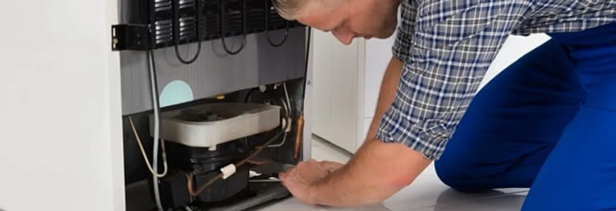 Refrigerator repair technician servicing the compressor and condenser area in Boise, ID