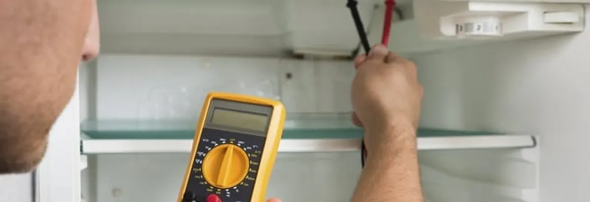 Refrigerator repair technician testing electrical components with a multimeter in Boise, ID