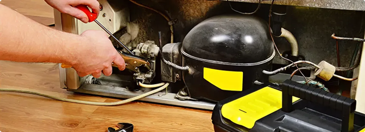 Refrigerator repair technician fixing the compressor and wiring in Boise, ID